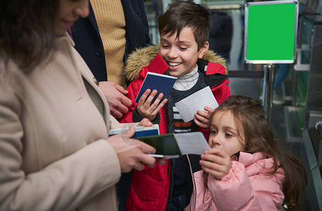 海关监管快乐的孩子享受家庭旅行 在机场通过护照和海关检查时将护照交给母亲背景