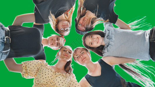 快乐的女孩朋友拥抱 在绿色背景的圆圈里高清图片