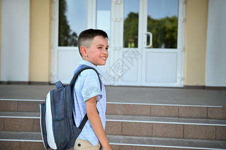 英俊的小学生站在学校大楼前的楼梯上 望着远方看一眼 复制空格背景图片