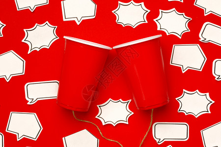 红色框玩具电话 由塑料杯和红色背景 有言语泡沫的绳索制成塑料说话金属话框讲话细绳背景