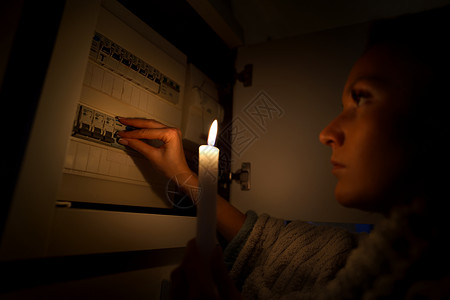 熄灯在停电或停电期间 在完全黑暗中调查家中保险丝盒的妇女 没有电的概念背景