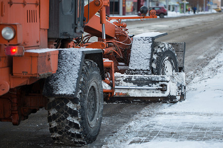 雪中城市拖拉机从雪中清理道路 挖掘机清理城市中大量积雪的街道 工人在冬天从道路上扫雪 从暴风雪中清洁道路雪堆雪机卡车男人车轮路人机器清洁背景