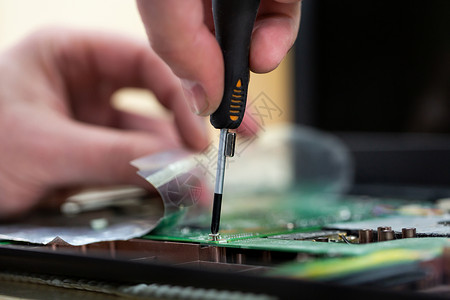 年轻男性技术员或工程师修理研究设施的电子设备 男子用磁螺丝起子拆卸一台计算机 (电磁螺旋桨)定影高清图片素材