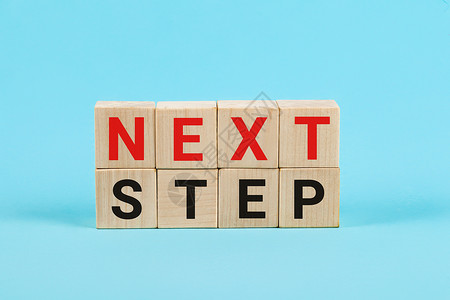下一步概念与木制立方体上的字母 教育和创业概念 蓝色背景小木方块上的下一步字样战略时间商业动机领导行动指导成功进步生长背景