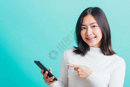 妇女微笑 她拿着并打短信女孩青少年女士短信互联网工具头发网络技术手机亚洲人高清图片素材