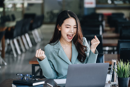 考后分析商业金融和投资 一位女商务人士通过放在桌子上的电脑在互联网上成功投资股票市场后表达了幸福文档统计预算库存技术微笑基准成人报告经理背景