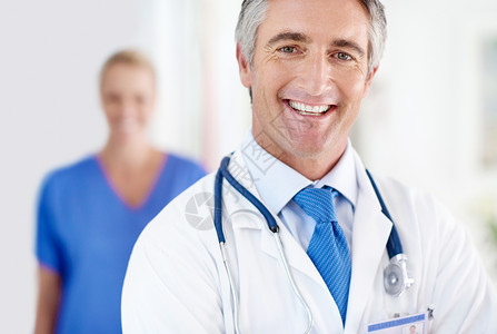 我们患者的健康是最重要的 一位男医生和一位同事站在背景中的画像背景图片