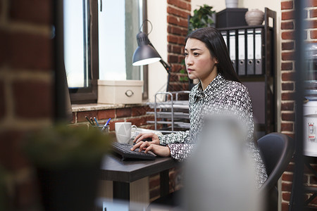 自信的办公室女职工在使用工作计算机和坐在办公桌旁的同时 重新推出总体项目营销理念对话高清图片素材