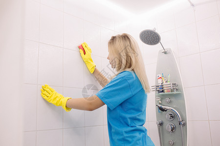 肮脏黄色瓷砖有特别清洁海绵清洗墙的女人 在浴室的地板上拉平了背景