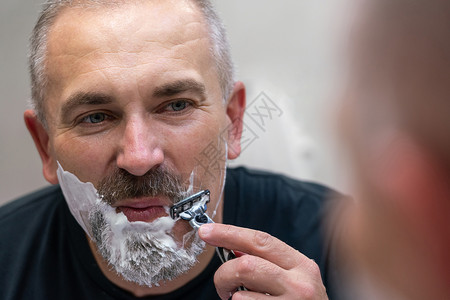 中年英俊男子在浴室刮胡子时剃胡子剃须膏成人卫生剃须剃须刀皮肤刮胡子护理男性剃刀须后水高清图片素材