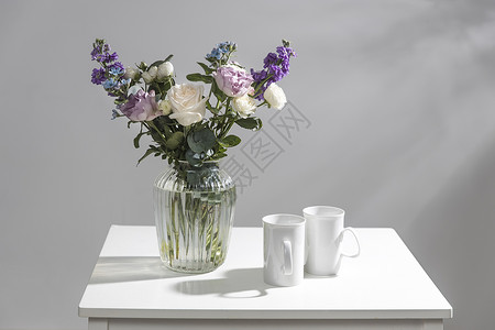 玻璃花瓶中的黑叶 紫色和白玫瑰 小茶玫瑰 印度马提奥拉和蓝色虹膜背景图片