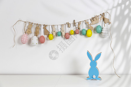 内部的片段 为复活节装饰的儿童房 墙上挂着一个用硬纸板剪成的塑料鸡蛋和兔子组成的花环 木蓝兔 您的文本的地方 复活节贺卡背景图片