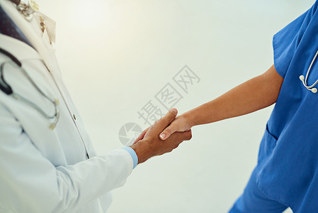 合作在医学上大有作为 两名身份不明的医疗保健从业者在医院门厅握手的高角度镜头背景