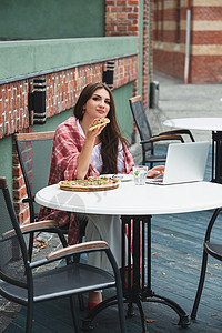 年轻的自由职业妇女使用笔记本电脑 坐在咖啡桌边吃披萨笔记职场自由职业者技术工作写作学习工人互联网女孩微笑高清图片素材
