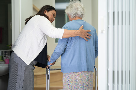 护理员帮助年老或年老的老年妇女在家中楼梯上行走时配有助行器日常生活护士平衡房子护理服务助手医院损失女士背景图片