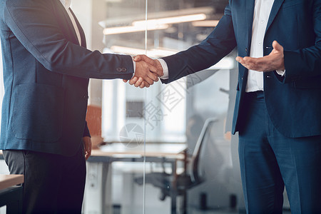 商界人士握手 在现代办公室完成一个会议后与商业界人士握手背景图片