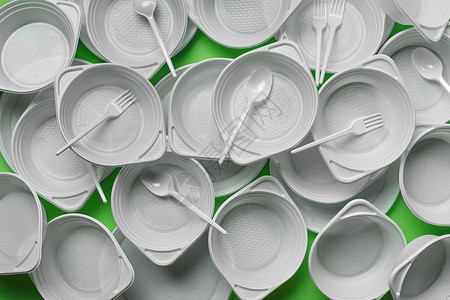 一次性塑料餐具在绿色背景的白色塑料一次性餐具与拷贝空间 野餐用具的概念 顶视图 选择性的焦点 特写环境派对厨具盘子生态生日食物用具产品烹饪背景