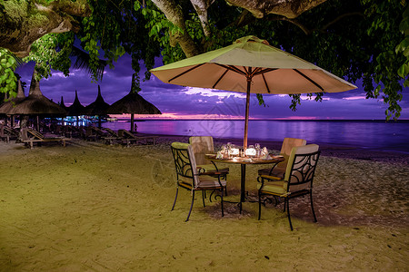 海滩在晚上毛里求斯海滩日落 豪华餐厅 有雨伞和椅子在沙滩上吃晚饭蜜月夫妻女士婚礼天空旅行奢华天堂庆典玻璃背景