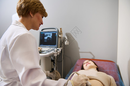 盆腔一位自信的女性妇科医生在怀孕的早期阶段就用现代超声波机器对孕妇进行检查 她很自信背景