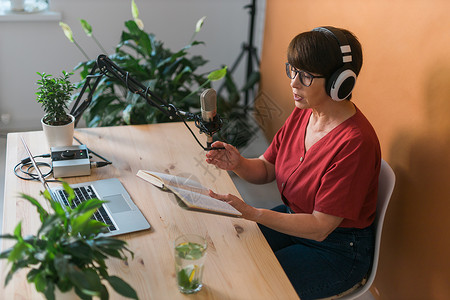 中年女电台主持人为在线节目制作播客录音  广播和 DJ 概念播送工作室笔记本耳机嗓音职业商业办公室打碟机音乐电脑高清图片素材