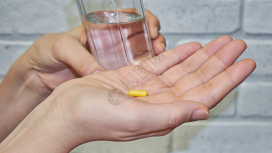 女人的手握着一粒药丸流感治疗手指剂量保健发烧吃药药品女性药店背景图片