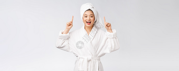 年轻女性的美容肖像显示并指向空空间复制 浴袍中的亚洲美护理治疗广告身体浴衣温泉成人手指展示成功背景图片