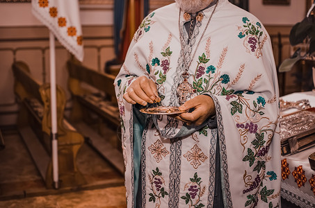 一个白领的牧师拿着一个配有轻亮金婚戒指的碟子施洗高清图片素材