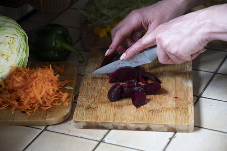 一名妇女以新鲜蔬菜为背景 在厨房切开甜菜木板食物厨师食谱桌子饮食木头沙拉营养女士抗氧化剂高清图片素材