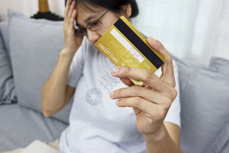 收税部女性的近手握着信用卡 感到压力很大 不开心 担心网上购物过度购物问题带来的收税债务负担背景