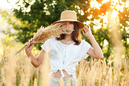 日落时站在小麦田上站着的年轻女孩 手伸展的少女太阳假期自由阳光女性闲暇农田帽子男人冥想快乐的高清图片素材