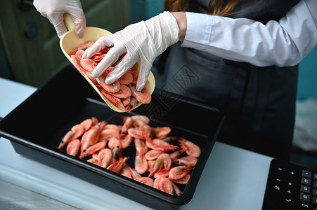 鱼贩站在柜台后面 停机坪工作 把新鲜冷冻冷冻的红虾放在盘子上;地中海鱼类市场营养高清图片素材