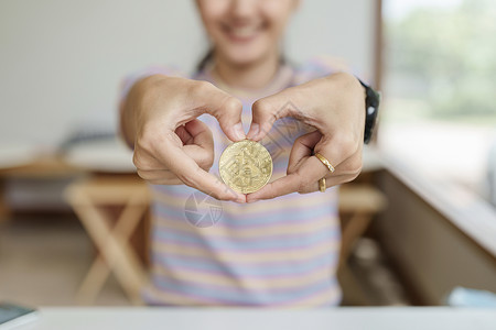 一枚心形奖牌是数字货币 女性手握计算机准备好的比特币硬币来投资来自未来数字或想象世界的资产 财务 投资 风险管理现金密码令牌金融密码学银行交背景