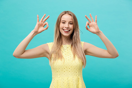 快乐的年轻女子展示好牌 用手指和大笑容 指着蓝背景被隔绝的笑容学生头发微笑黑发女孩商业白色成人手势女士象征高清图片素材