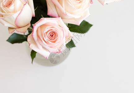 有小鱼花瓶白桌上玻璃花瓶中粉红花和奶油玫瑰的高角视图(有选择性地聚焦)背景