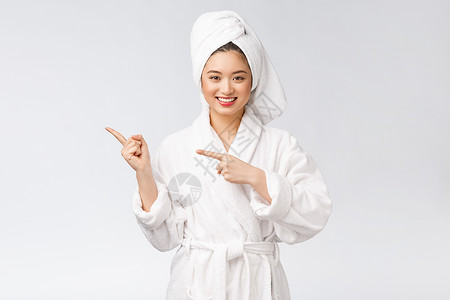 年轻女性的美容肖像显示并指向空空间复制 浴袍中的亚洲美护理身体温泉微笑成功广告治疗快乐女士手指背景图片