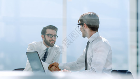 在服务台与雇员握手工人同事笔记本代理人电脑标签会议桌子办公室男人成功的高清图片素材