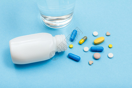 糖衣药片白瓶 有不同的药丸 胶囊和水杯背景