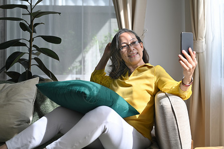 带着智能手机给朋友或亲戚打视频电话 享受愉快的谈话的快乐退休妇女 她们玩得开心高级的高清图片素材