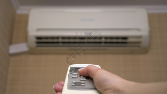 花型关闭按钮房子里的空调可以调节房间的温度 一位女士使用遥控器打开空调 特写 空调模糊背景