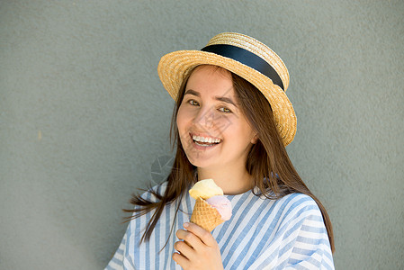 吃冰淇淋女孩戴草帽的女潮人正在吃冰淇淋锥体乐趣城市女孩女士裙子喜悦快乐女性太阳镜背景