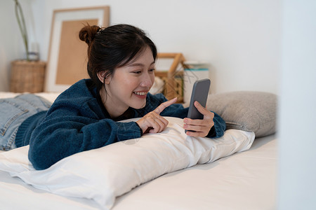 使用智能手机打字 在卧室聊天盒里聊天 社交媒体制造概念等手艺快乐的亚洲女性手工作网络笔记本长椅休闲装微笑男人女士成人视频现代的高清图片素材