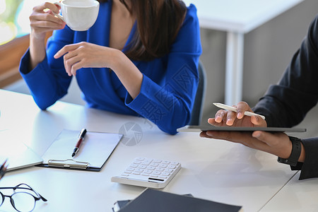 裁剪拍摄的女商务人士拿着咖啡杯 与办公室的同事讨论项目战略成人高清图片素材