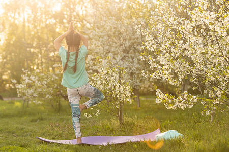 优秀是一种习惯一个小女孩做瑜伽 躺在公园体育垫子上 健康的生活方式是一种幼稚习惯 笑声后院青年生活运动训练后代冥想活动喜悦女孩背景