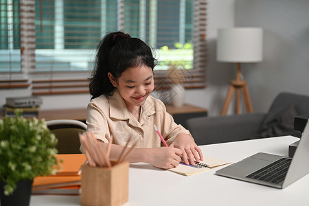 在家用笔记本电脑在网上学习的亚洲快乐儿童做功课书高清图片素材