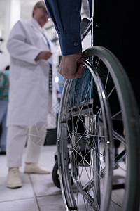 在预约时在医生面前用轮轮椅拉着大男子手的近距离检查绳索高清图片素材