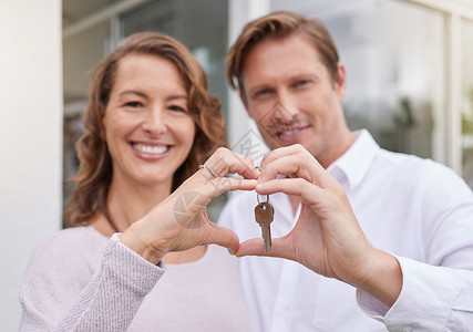 幸福的已婚夫妇的特写手举着心形手势的新房钥匙 男人和女人拿着新房子或公寓的钥匙生活高清图片素材