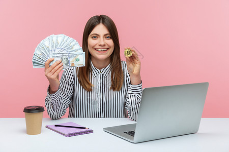 坐在钱上女人有情感的年轻女性 坐在办公室工作 有粉红色背景购物电子商务商业电脑货币金融笔记本利润储蓄职场背景