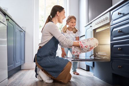 我们的下一步是让它凉快下来 一个女人和她的女儿在把东西从烤箱里拿出来时 看上去很兴奋背景图片