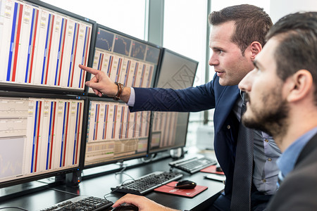 股票交易商在看计算机屏幕上的市场数据分析高清图片素材