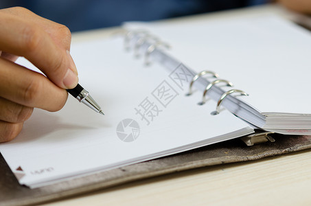 纸人紧紧握着一支笔 写在笔记本上笔记写作作家日记手指教育铅笔学习文档桌子背景